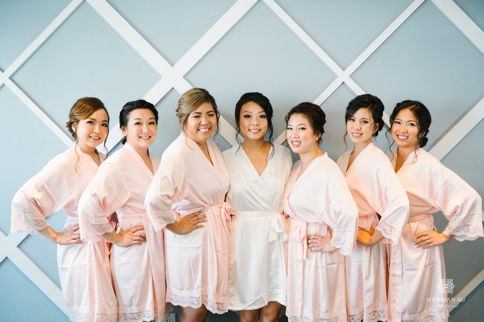 Bride standing in between three bridesmaids on one side and three on the other all wearing robes