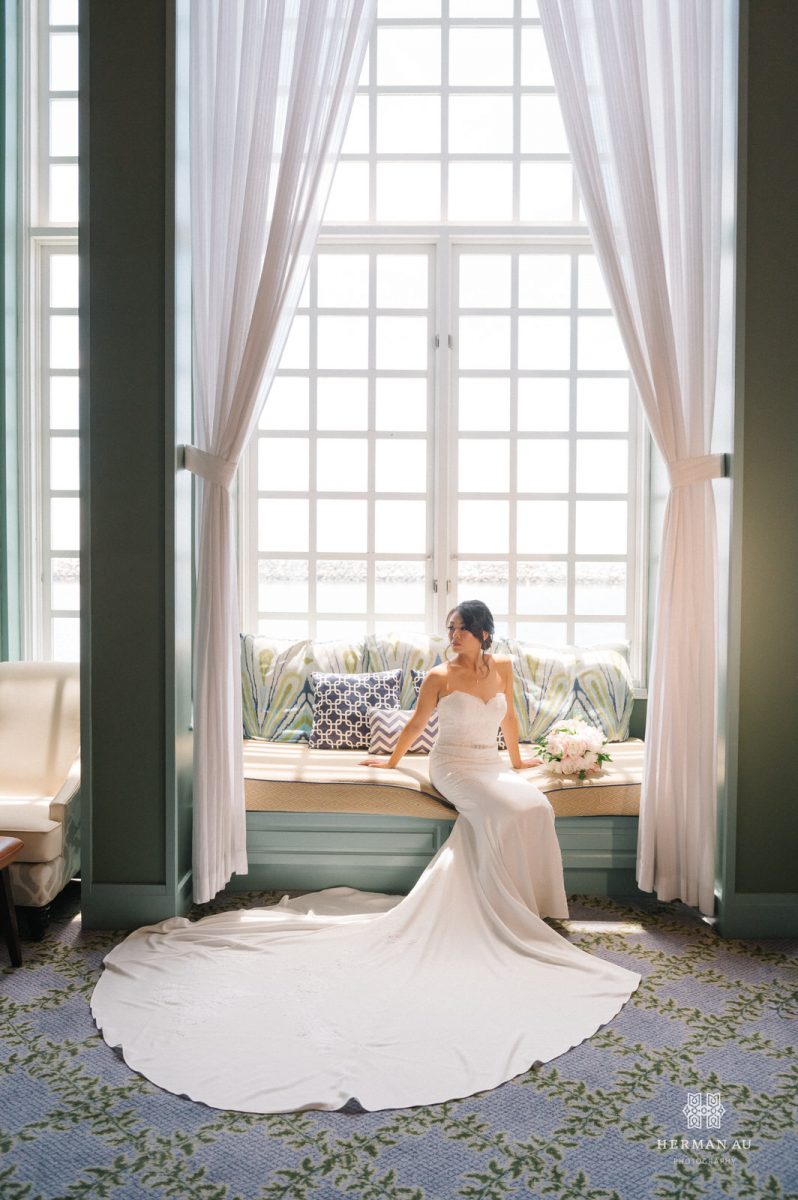 Bride sitting on a bench in front of the window at the Portofino Hotel