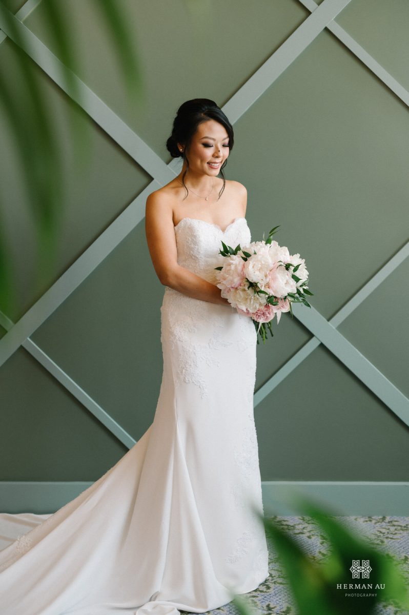 Bride smiling and staring sweetly at her bouquet in her dress