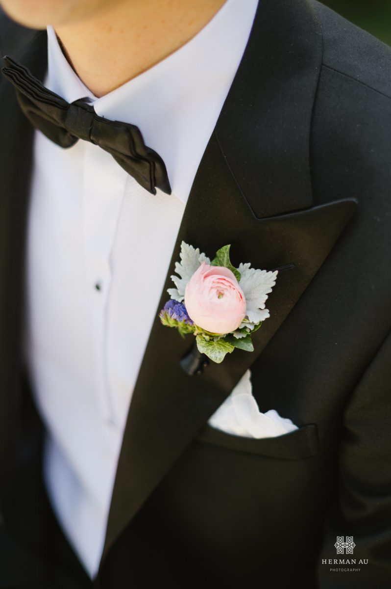 Close up of groom's boutonniere with tuxedo as the background