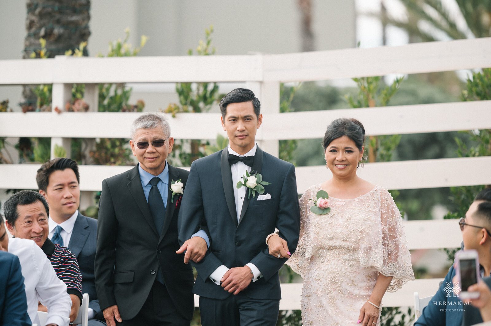 The groom being walked down the aisle by his parents